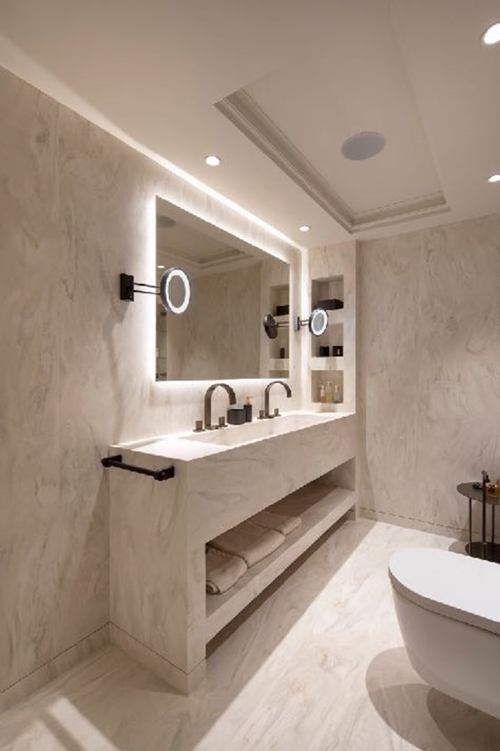 Zemin ve duvar kaplaması, kusursuz bir şekilde bütünleştirilmiş lavabo ile lavabo ünitesi, havlu askısı ve nişler Corian<sup>®</sup> Carrara Crema renginde (solda). Küvetin arkasında, Corian<sup>®</sup> Smoke Drift Prima ile kaplı duvar, gizli aydınlatma ile tamamlandı. Tasarım: Soliform; fotoğraflar © Dian Stanchev, tüm hakları saklıdır.